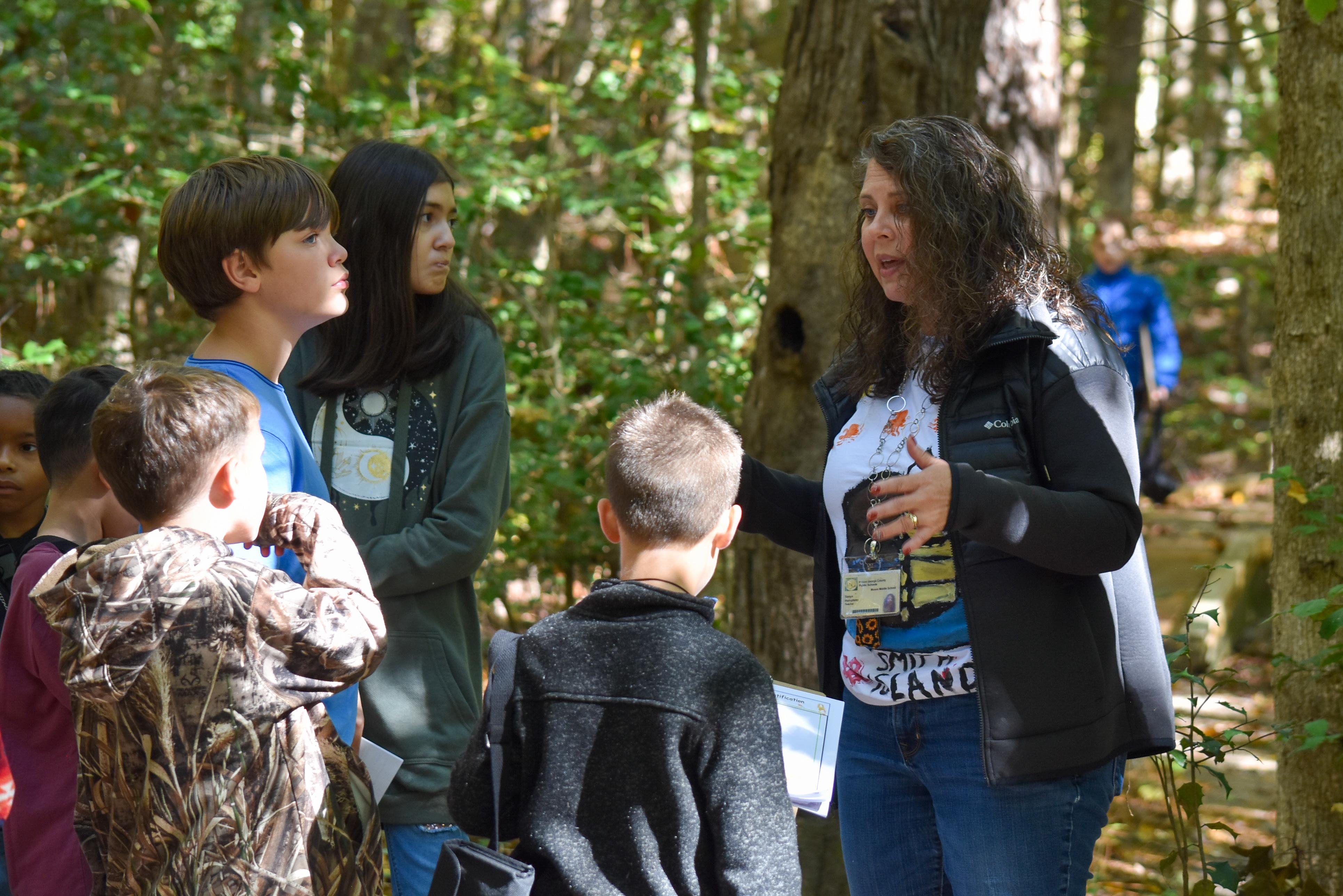 Another teacher explains ecology concepts while along the trail with students